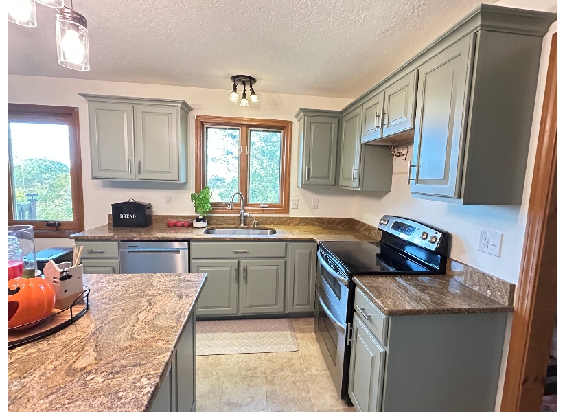 After cabinet refacing in Belchertown MA — same kitchen with new sage green shaker-style doors, brushed nickel hardware, and crown molding