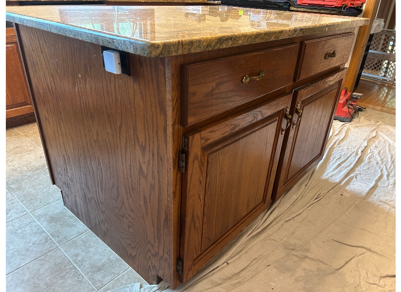 Before kitchen island refacing in Belchertown MA — worn dark oak island with raised-panel doors and dated brass pulls