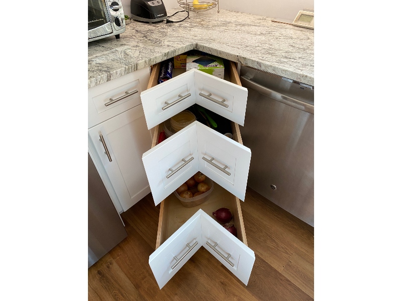 Corner drawer cabinet solution — two angled drawer fronts opening together to access full corner cabinet storage