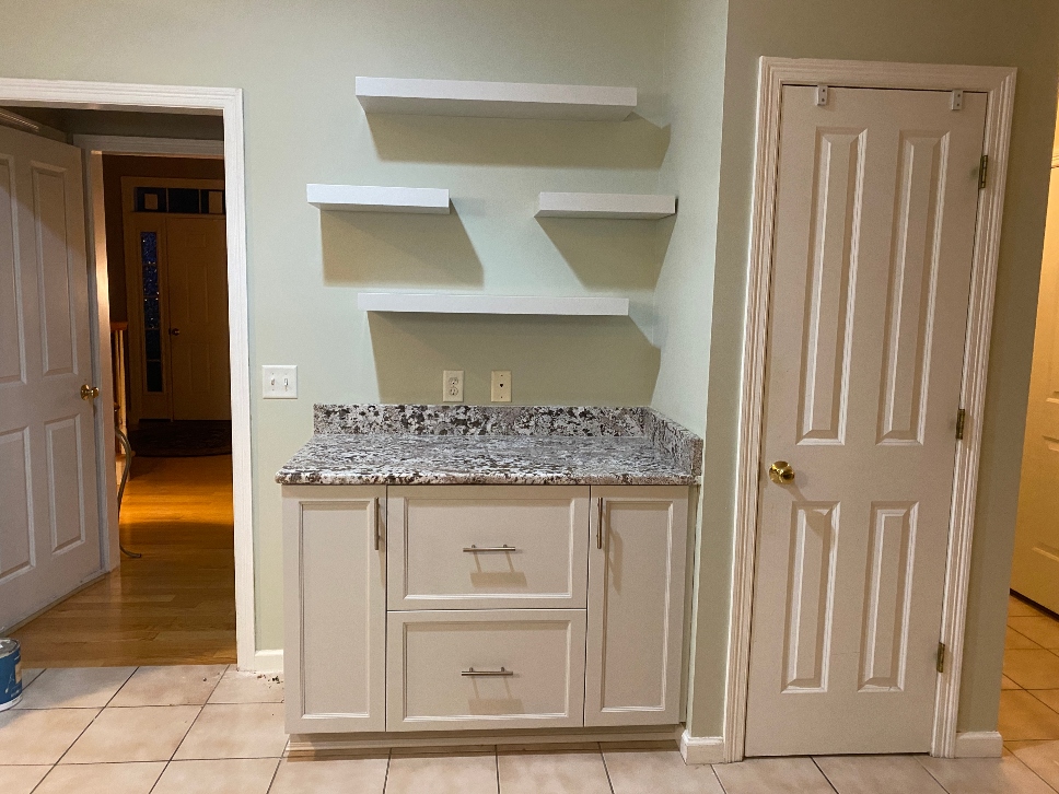 Painted floating kitchen shelves installed alongside painted cabinets