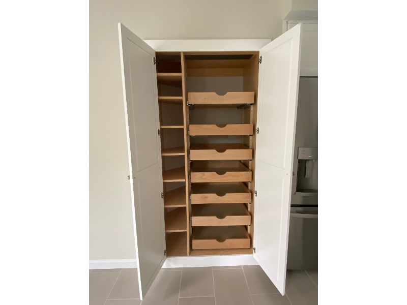 Custom built-in pantry cabinet open showing organized interior
